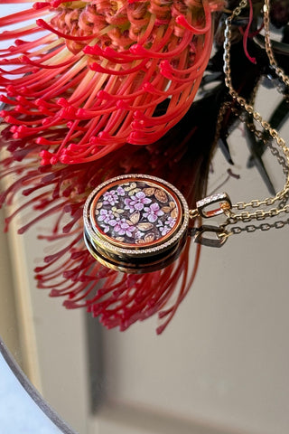 A fantastic Aurora pendant. The finest painting of soft pink orchids surrounded by butterflies on a noble dark grey background represents luxury, splendour and exclusivity. VARVARA collection. 74 sparkling diamonds, 18K yellow gold.